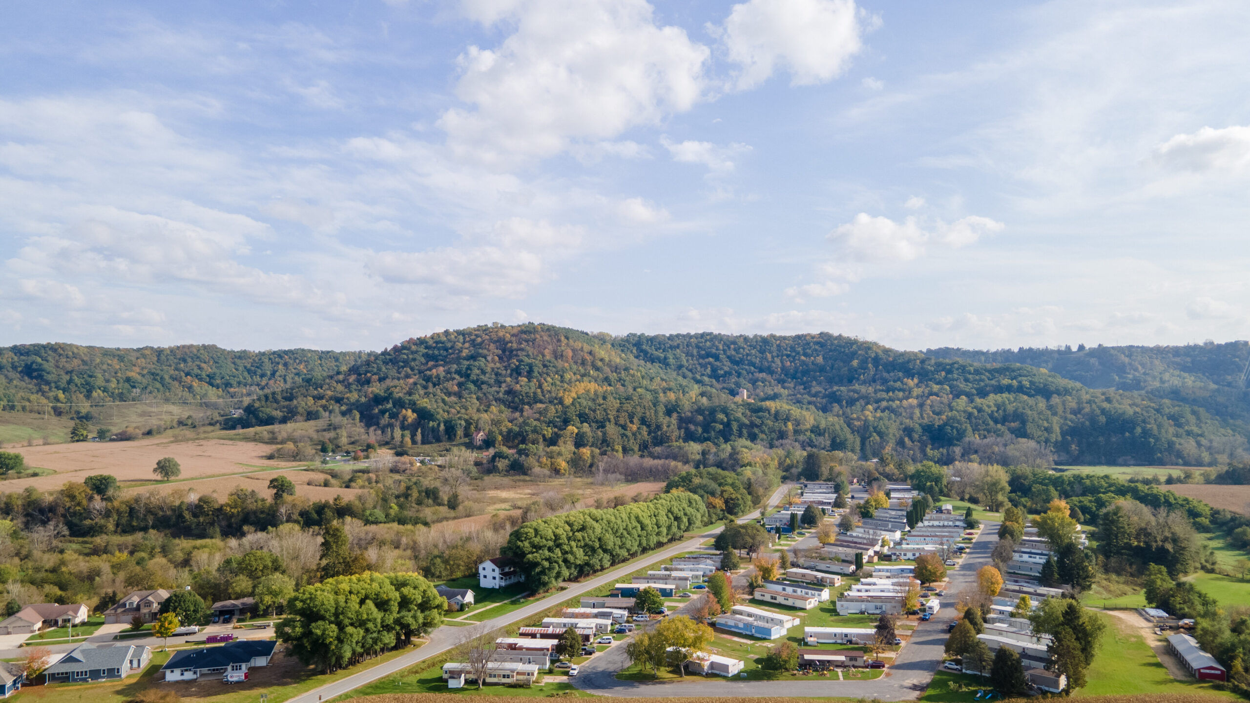 rural neighborhood and farm land in autumn in midwest; mountains with trees and open landscape; farm fields after harvest; family friendly single-family homes and mobile home park for diversity.