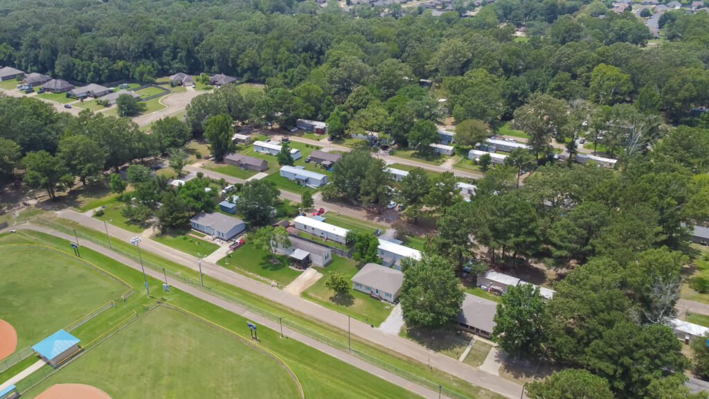 Large baseball fields near row of manufactured, modular, and mobile homes in Richland, Rankin County, Mississippi suburb of Jackson, lush green trees neighborhood
