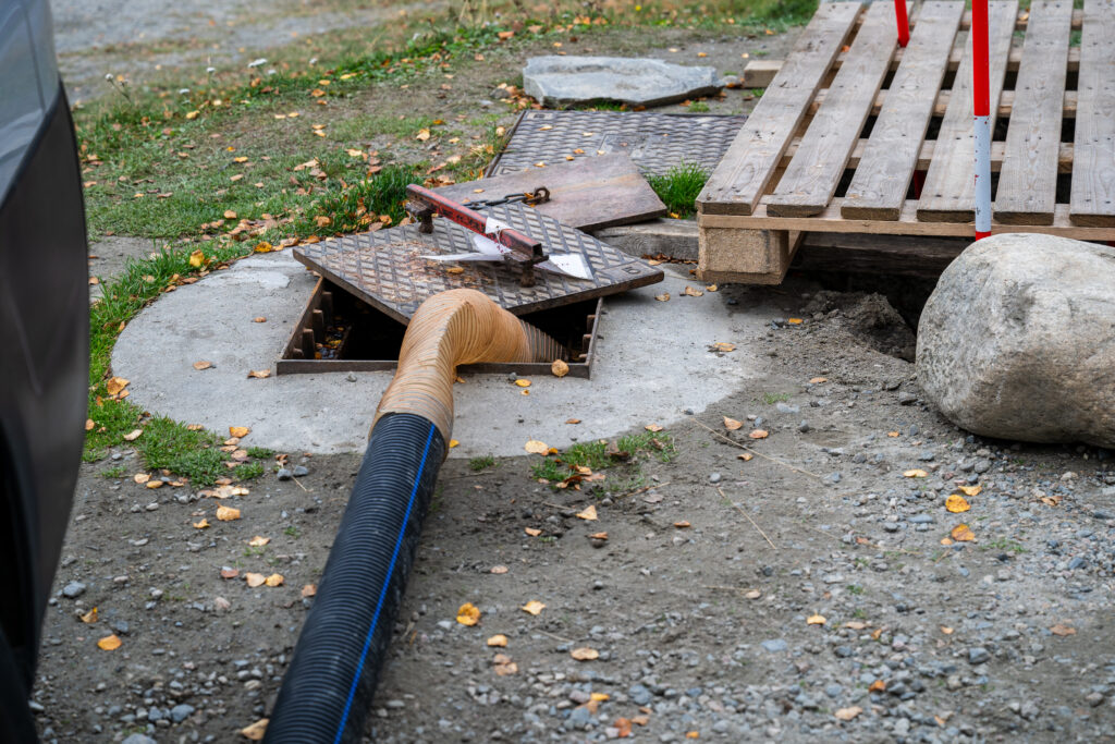 Camper van wastewater hose connected to sewage drain at service station